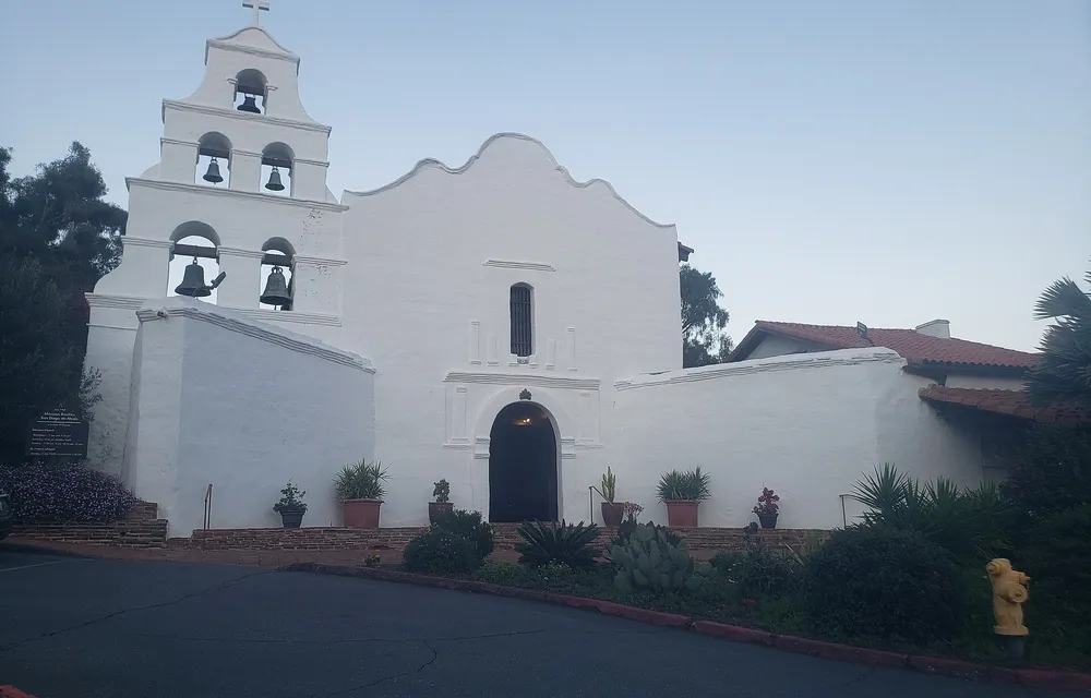 The white bell wall and church facade of Mission San Diego de Alcala